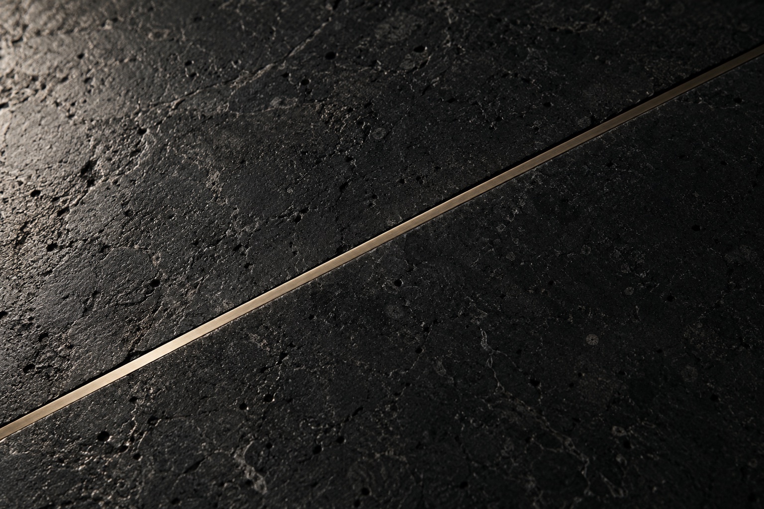 A close study of honed black limestone meeting a restrained satin champagne seam